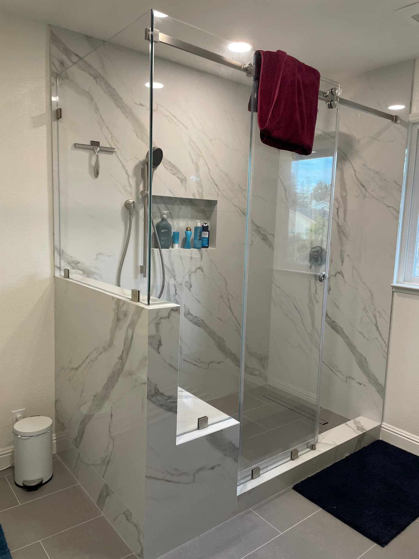 Walk-in shower with frameless sliding glass and marble-look porcelain walls