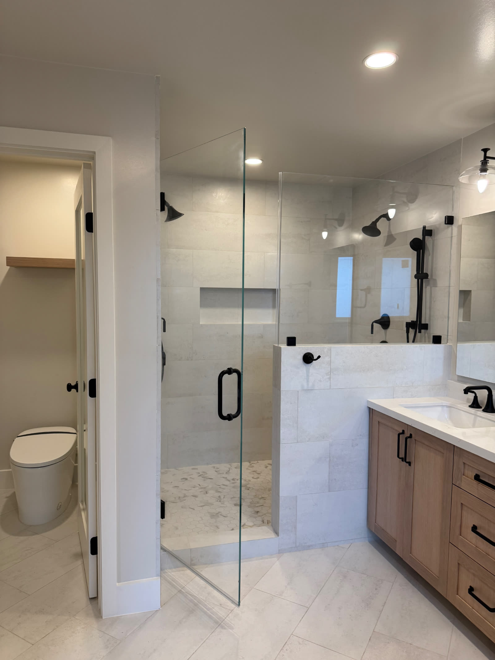 Remodeled primary bathroom with frameless glass shower and white oak double vanity